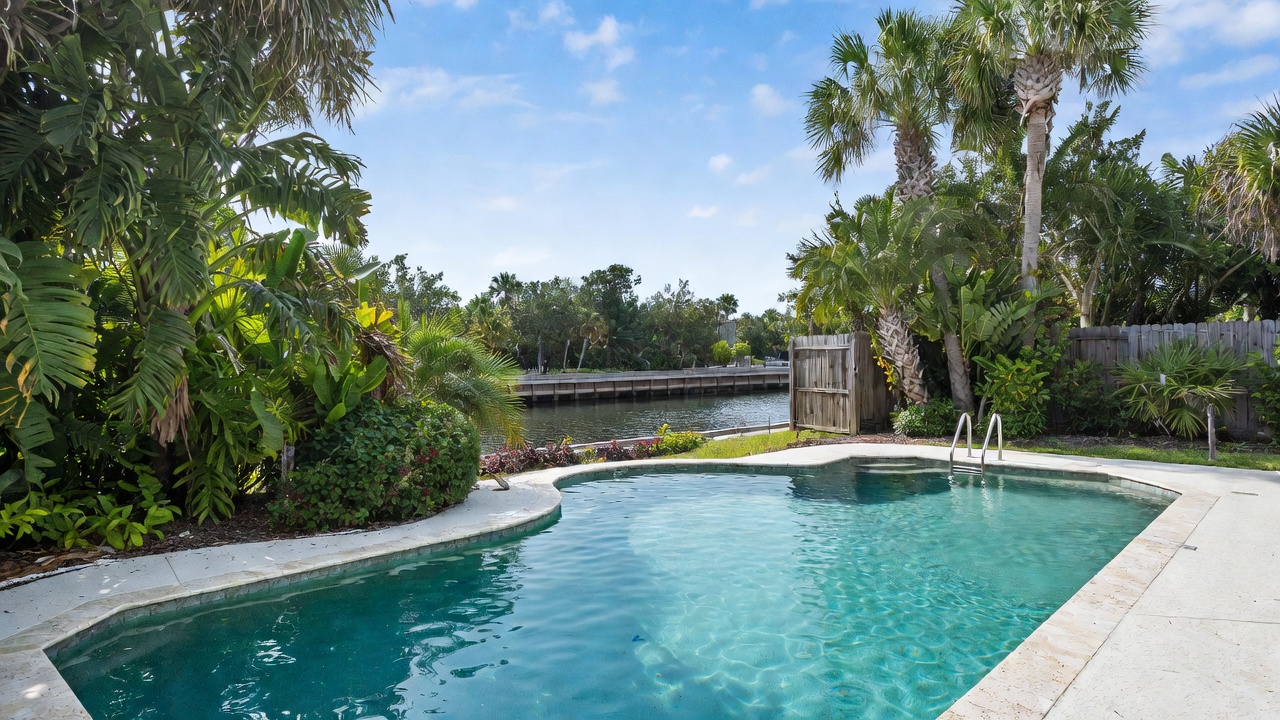 Crystal clear backyard pool with tropical palm trees and canal view in Cape Coral, Florida